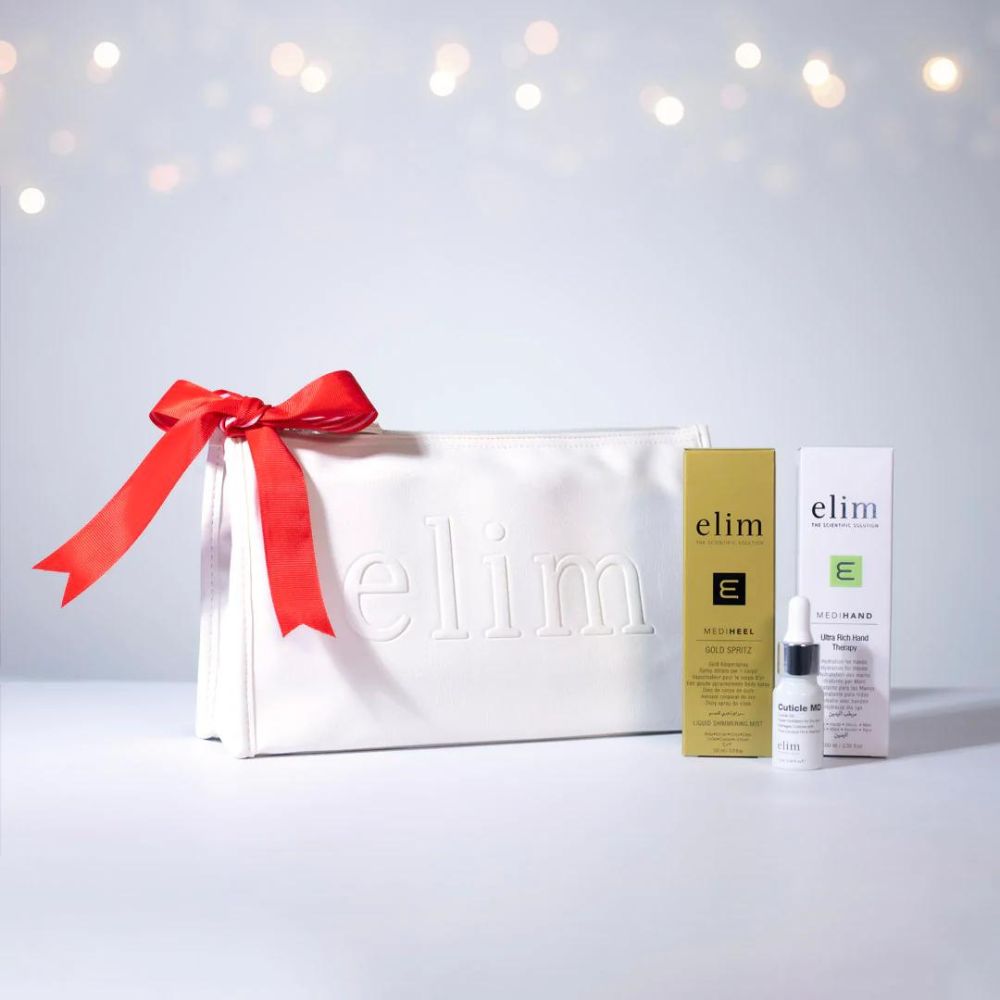 Elim Festive Gift Set displays a white embossed bag with the Elim logo and includes a tube of Elim Ultra Rich Hand Therapy, a bottle of Gold Spritz and a dropper bottle of Cuticle MD